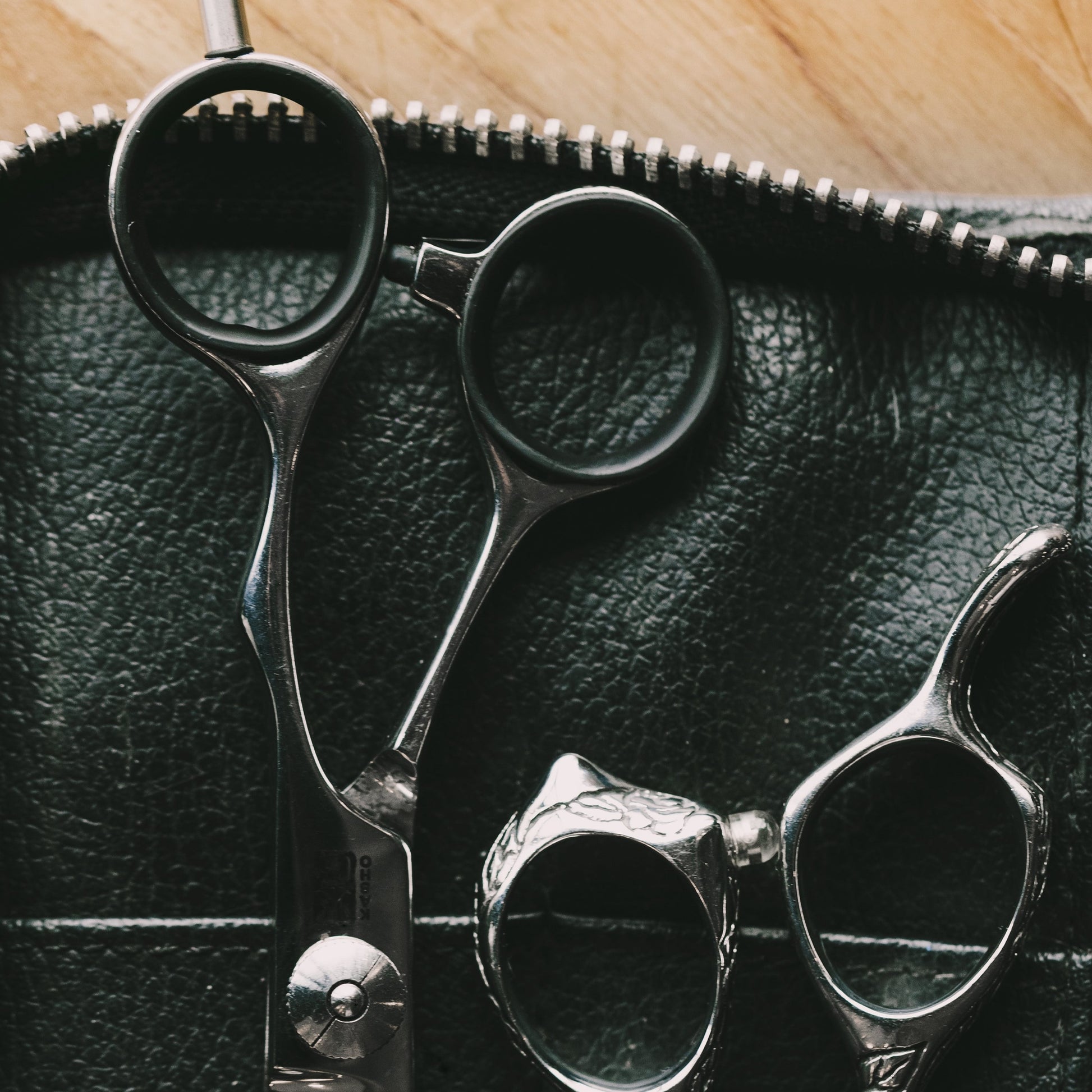 A Hairdressers tools in a leather case showing scissors and thinning tools.