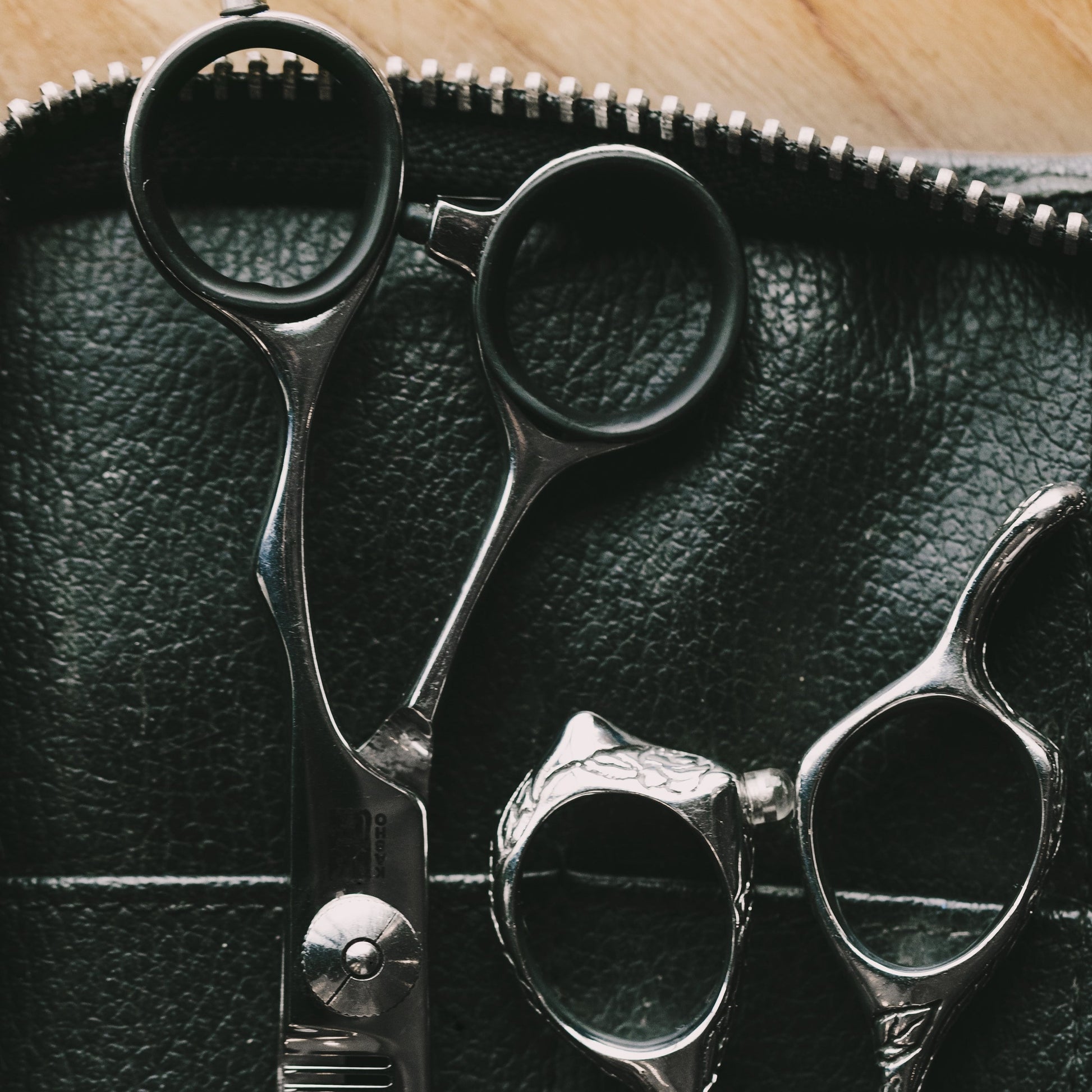 A Hairdressers tools in a leather case showing scissors and thinning tools.